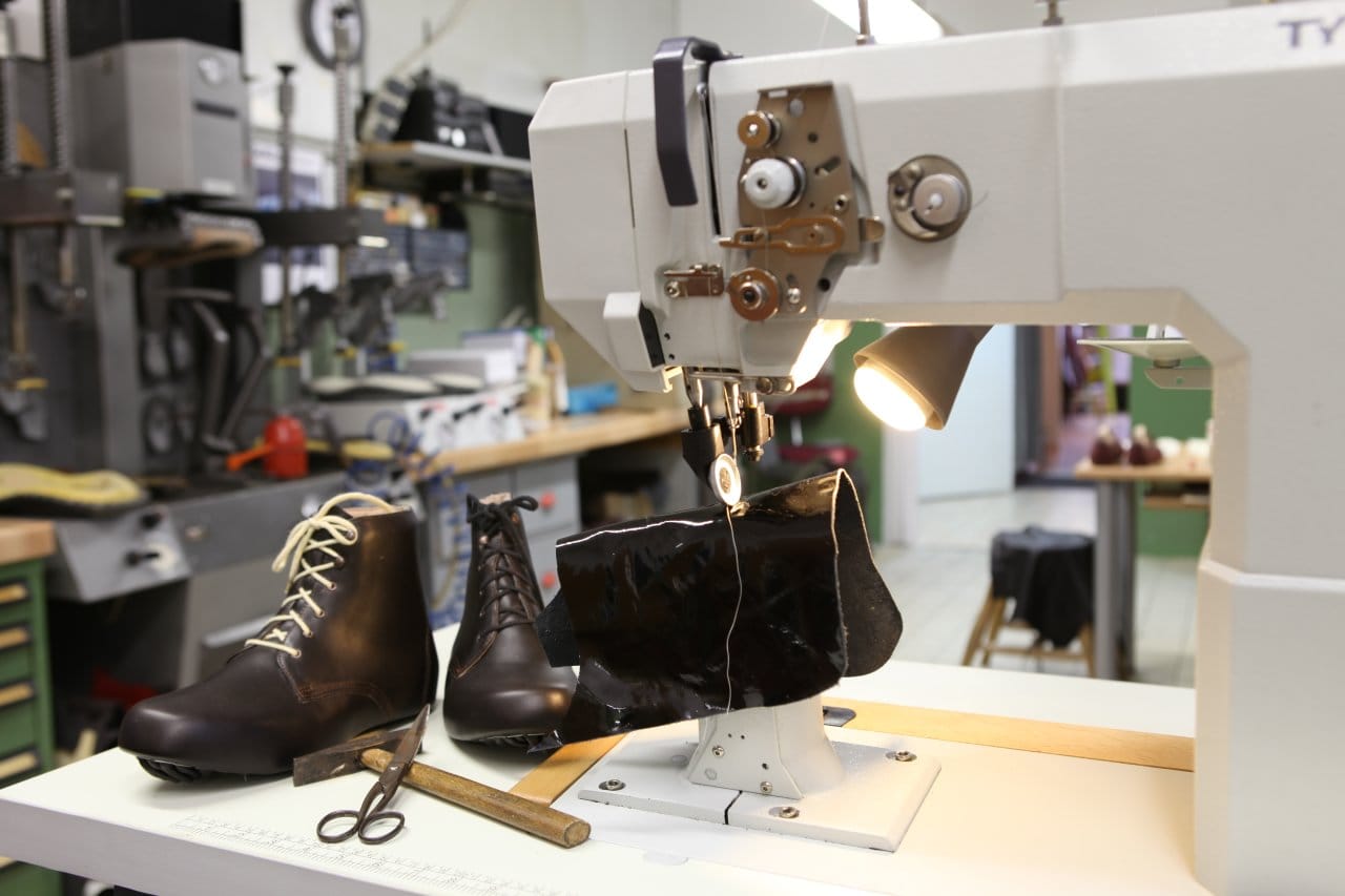 Maßgefertigte Lederstiefel neben der Nähmaschine in der Werkstatt